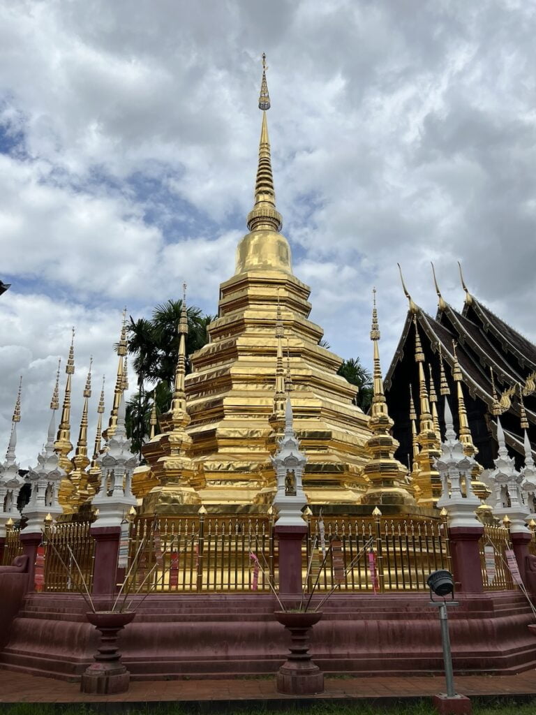 A golden pagoda in front of a cloudy sky, showcasing the beauty of Thailand.