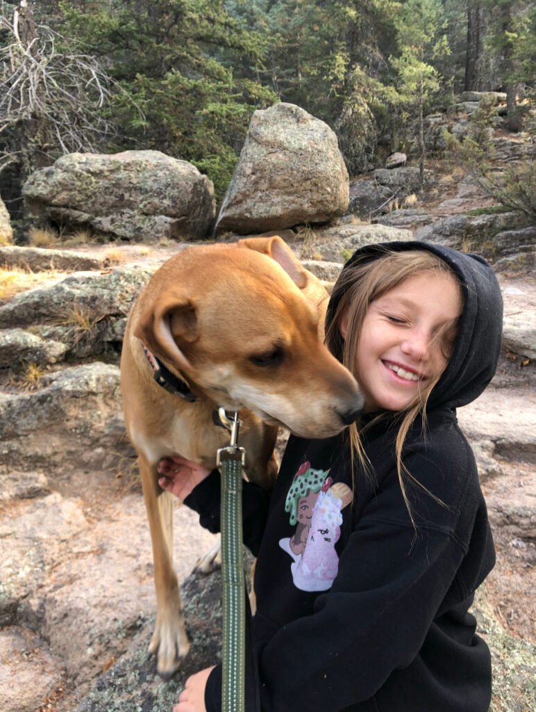 First-Time Tent Camping With Your Dog: Tips & Checklist To Be Prepared! 10 A young girl with a brown dog on a rock.